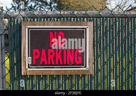 No Parking sign on a green chain link fence. Stock Photo