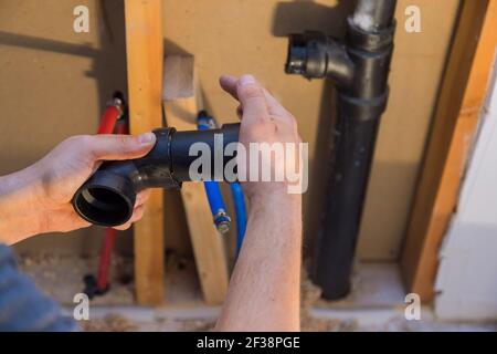 Plumber joining PVC sewage drain pipes on a home under construction Stock Photo