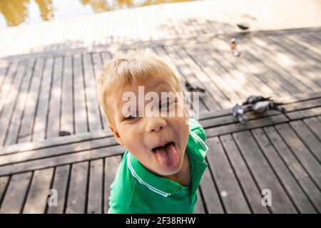 Funny little kid showing tongue in park Stock Photo