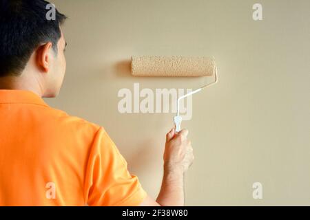 Back view of a painter painting wall with roller Stock Photo