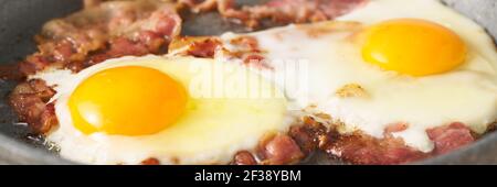 Long banner with keto meal fried eggs with fat bacon, two yellow yolk with fried pork, ketogenic Stock Photo