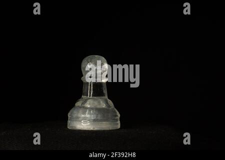 single clear pawn chess piece isolate on a black background with yellow light