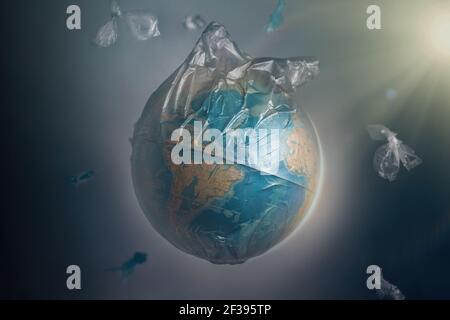 Globe of planet Earth dressed in a garbage plastic bag. Fly around the pieces of broken plastic. The concept of land pollution and ecological imbalanc Stock Photo