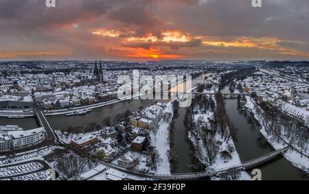 Panorama of Regensburg city in Bavaria with the river Danube the cathedral and the stone bridge in winter with ice and snow at sunset and snowstorm, G Stock Photo