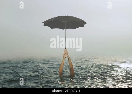 person clinging to an umbrella in the middle of the ocean tries to save his life, concept of success and failure Stock Photo