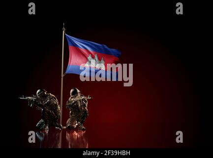 Concept of military conflict with soldier statues and waving national flag of Cambodia. Illustration of coup idea. Two guards defending the symbol of Stock Photo