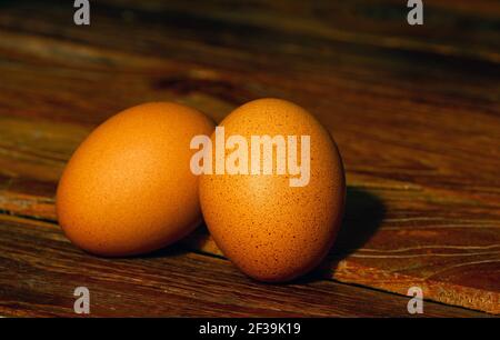 Two chicken eggs on the old teak table, in shallow focus Stock Photo