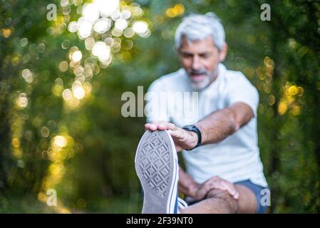 Mature man stretching his leg in forest Stock Photo