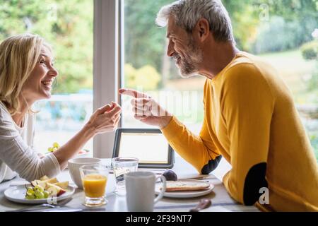 Smiling mature couple talking with each other while having breakfast Stock Photo