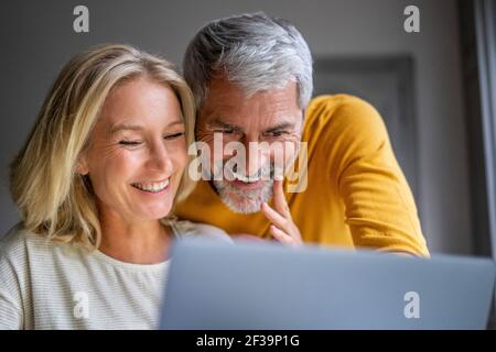 Smiling mature couple using laptop Stock Photo