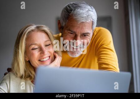 Smiling mature couple using laptop Stock Photo