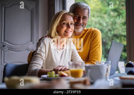Portrait of smiling mature couple using laptop at home Stock Photo