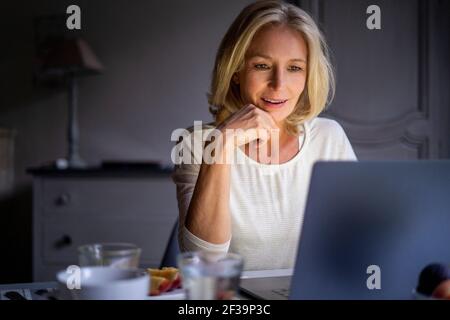 Smiling mature woman using laptop at home Stock Photo