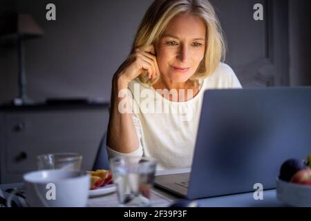 Smiling mature woman using laptop at home Stock Photo