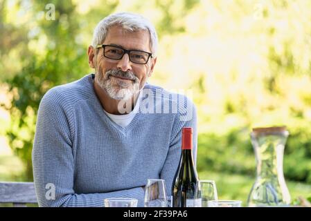 Portrait of smiling mature man leaning on table in backyard Stock Photo