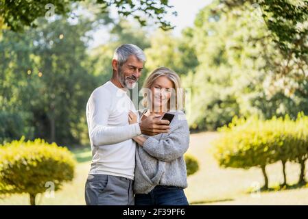 Smiling mature couple using smartphone in backyard Stock Photo