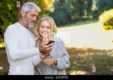 Smiling mature couple using smartphone in backyard Stock Photo