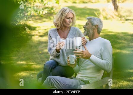 Mature couple talking while having coffee in backyard Stock Photo