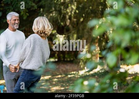 Smiling mature couple with holding hands looking at each other in backyard Stock Photo