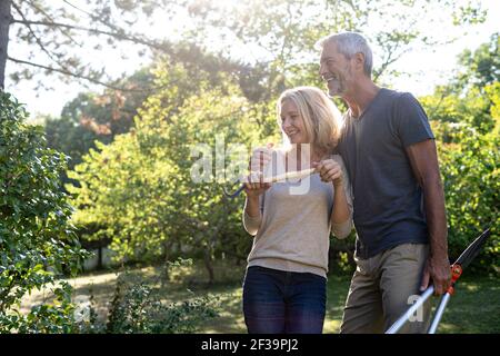 Cheerful mature couple with gardening equipment standing in backyard Stock Photo