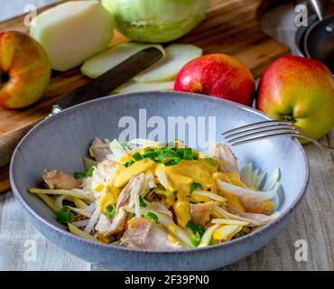 homemade Chicken salad with raw apples and kohlrabi strips served with a delcious curry sauce on kitchen table Stock Photo