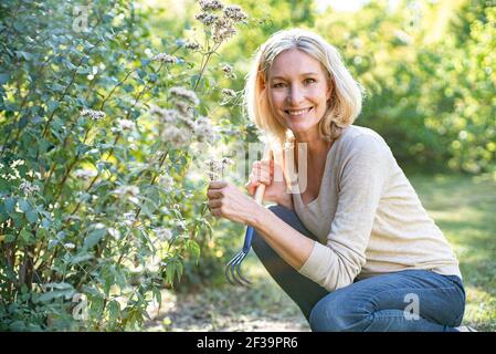 Portrait of smiling mature woman holding flowers in backyard Stock Photo