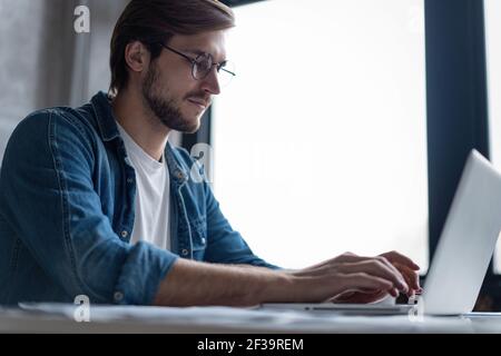 Successful entrepreneur smiling in satisfaction as he checks information on his laptop computer while working Stock Photo