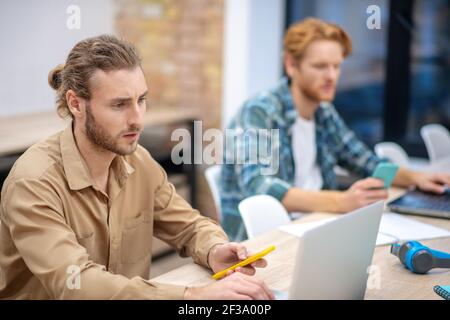 Busy day. Two guys looking serious while working on the laptops Stock Photo