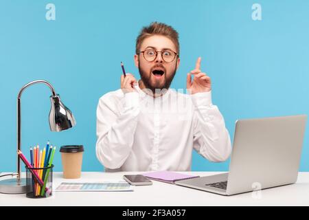 Excited man raising hands up and looking at camera with widely opened eyes and mouth, eureka, has good idea for start up, inspiration. Indoor studio s Stock Photo