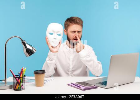 You are liar! Bearded man office employee touching nose with finger holding white face mask in hand, blaming in lie, suspecting of dishonest. Indoor s Stock Photo