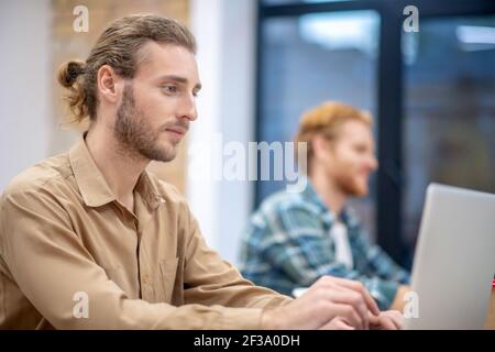 Colleagues. Two male colleagues working on laptops and looking involved Stock Photo