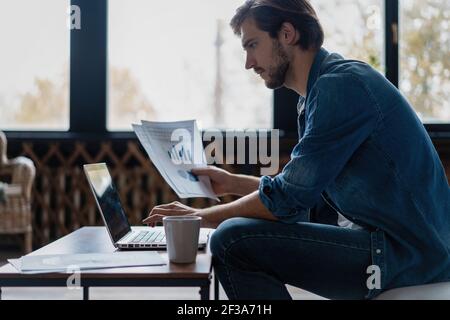 Entrepreneur working with a laptop and holding a document in a little office or home Stock Photo