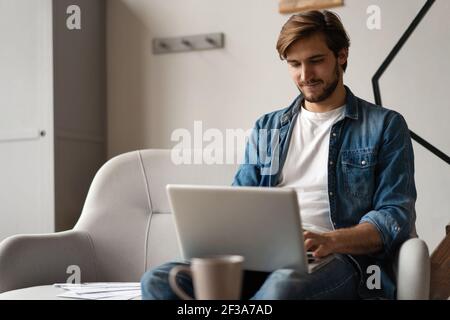 Successful entrepreneur smiling in satisfaction as he checks information on his laptop computer while working Stock Photo
