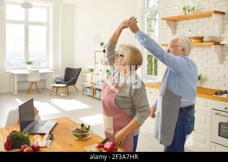 Positive senior couple having fun while cooking a healthy meal at home together Stock Photo