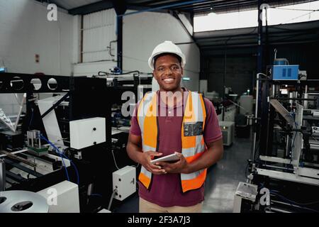 Portrait of a happy industrial engineer standing in factory with smart tablet Stock Photo