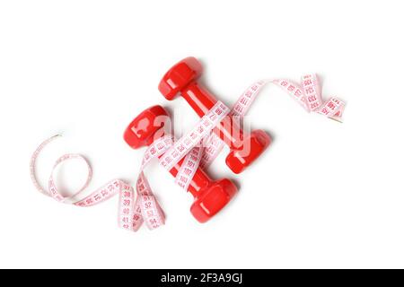Red dumbbells and a pink measuring tape isolated on white background, fitness and weight loss concept Stock Photo