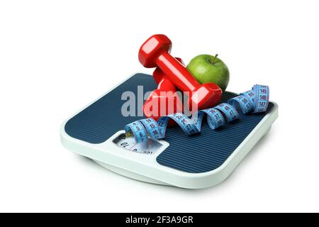 Bathroom scale with red dumbbells, a green apple and a blue measuring tape isolated on white, weight control concept Stock Photo