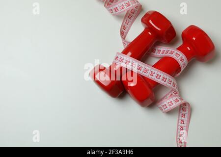 Red dumbbells and measuring tape on white background Stock Photo