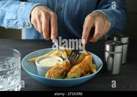 Woman eating fried fish and chips on dark table, close up Stock Photo