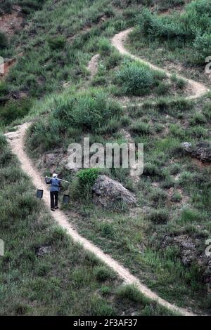 (210316) -- TAIYUAN, March 16, 2021 (Xinhua) -- File photo taken on June 28, 2010 shows Liu Qingji walking with a shoulder pole to fetch fresh water from kilometers away, in Shijiamao Village of Yukou Town in Fangshan, north China's Shanxi Province. Shijiamao is a small village located in rugged mountainous areas with little rainfall. Like other villagers here, Liu Qingji, an 85-year-old farmer, used to do farming at the mercy of the elements. Having dwelled many years in a gloomy 'yaodong', a house built into the hardened earth common across the Loess Plateau in northern China, Liu hoped to i Stock Photo