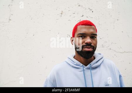 Pleased african american guy in wireless earphones looking at camera outdoors Stock Photo