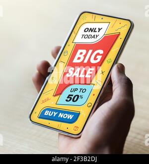 African American man holding smartphone with online shopping ad Stock Photo