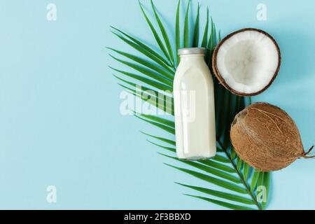 Bottle of coconut vegan milk and coconuts top view on blue background. Stock Photo