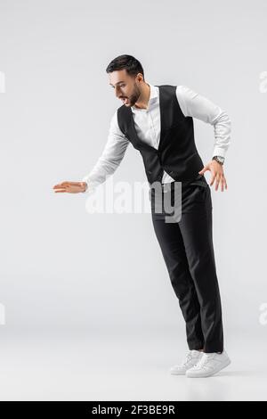 full length view of trendy arabian man imitating falling on grey Stock Photo