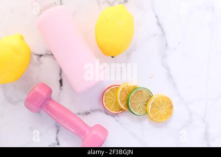 pink color dumbbell, water bottle and lemon on tiles background  Stock Photo