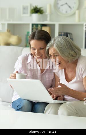 Mother and daughter sitting at table with laptop, at home Stock Photo