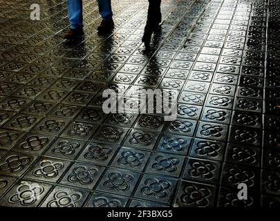 Barcelona, Spain. Couple legs and their reflection on wet flower street paving. Romantic vacation background. Stock Photo