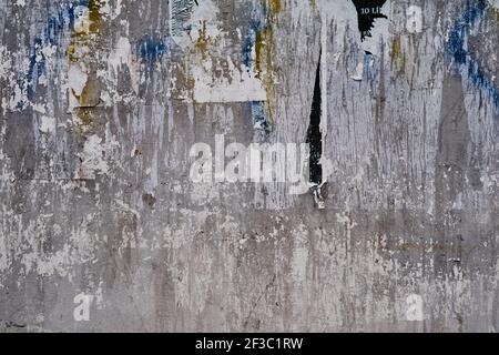 Old bulleting board wall with rests of worn peeled advertising posters, grunge background or texture Stock Photo