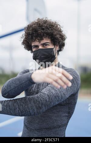 A closeup of a young athletic Spanish male doing arm stretches Stock Photo
