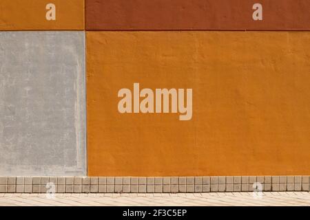 Orange, brown and grey painted wall with tiled baseboard, modern architecture detail, urban geometric abstract background or texture Stock Photo